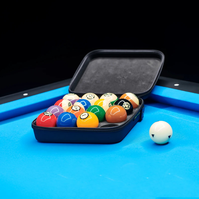 Set of pool balls in a black case on a pool table with a blue surface.