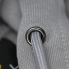 Close-up of a gray textured fabric with a metal grommet.